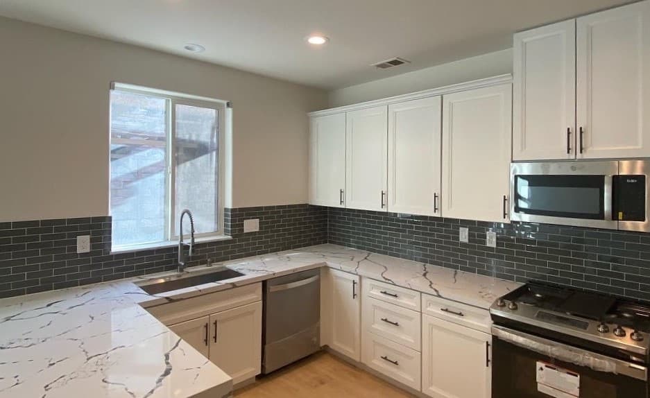 Remodeled kitchen with new white granite countertops and wooden cabinets